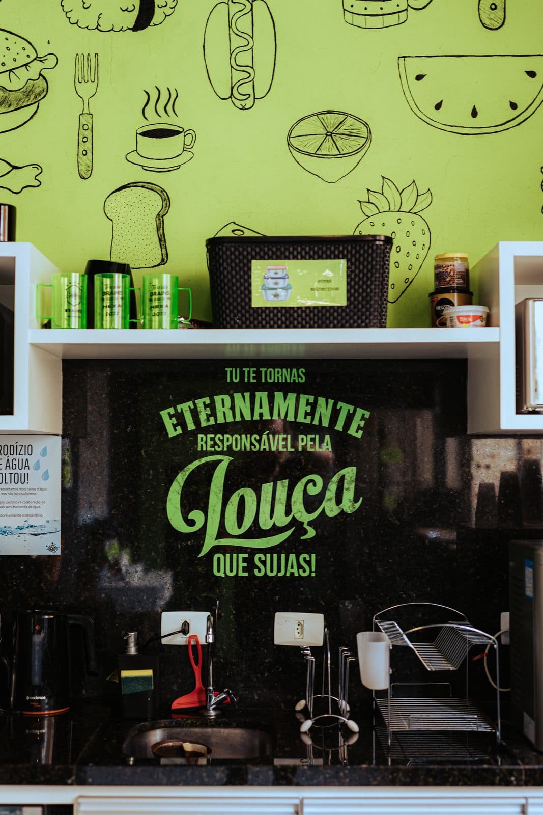 Cozinha compartilhada do Brains Batel, com parede ilustrada em verde-limão, em Curitiba