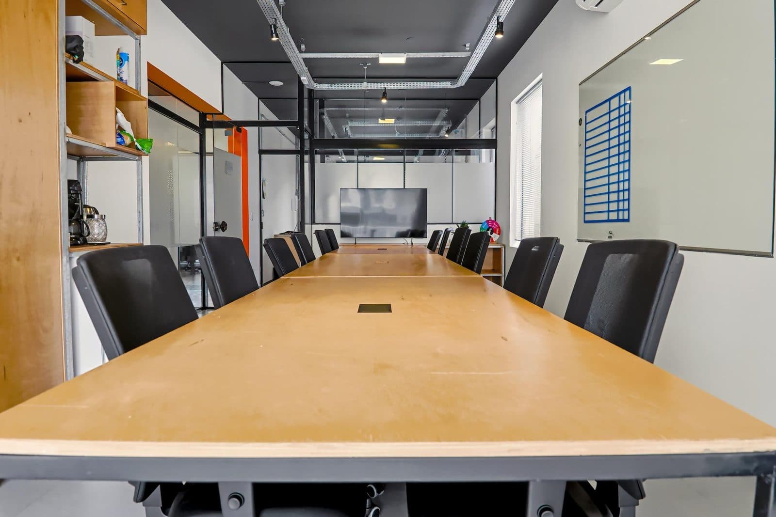 Sala privativa mobiliada do Brains Batel, com bancada clara e cadeiras ergonômicas, em Curitiba