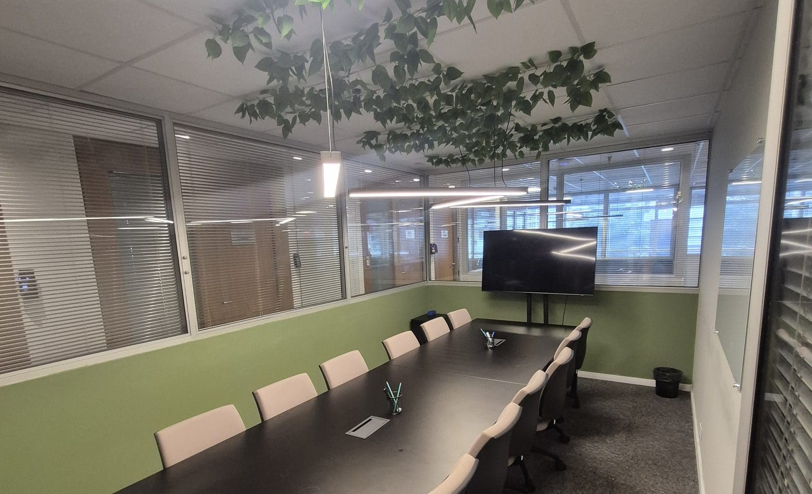 Sala de reunião do Brains Centro Cívico em Curitiba, com mesa longa, televisor e vegetação suspensa no teto