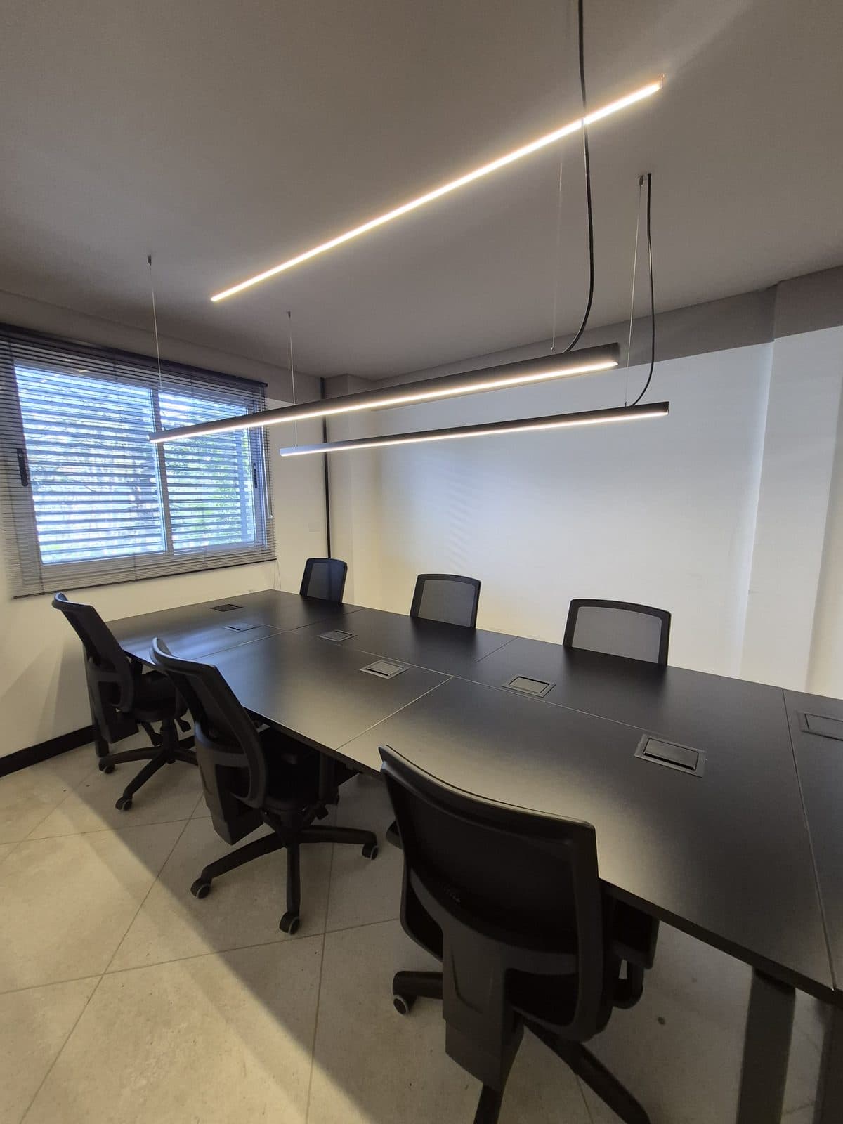 Sala de reunião do Brains Parque Barigui, com mesa longa e luminárias lineares, em Curitiba